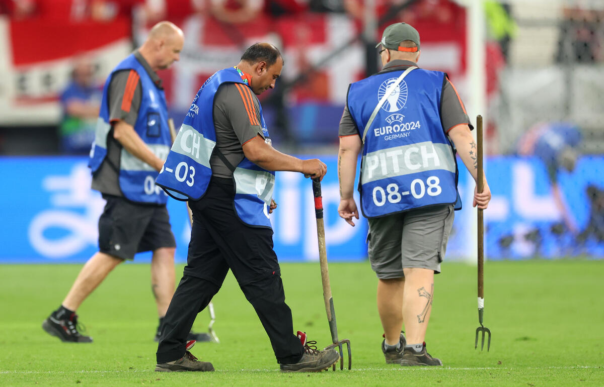 荒れたピッチを補修するスタッフ